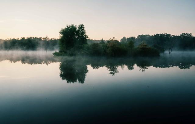 Mist hangs over a lake at dawn