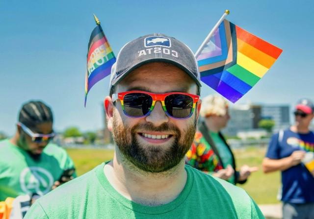 A man smiles with rainbow flags